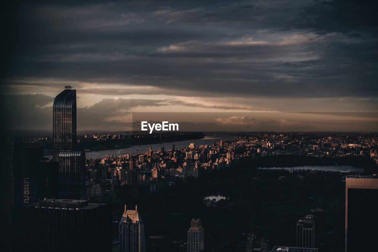 ILLUMINATED CITYSCAPE AGAINST CLOUDY SKY