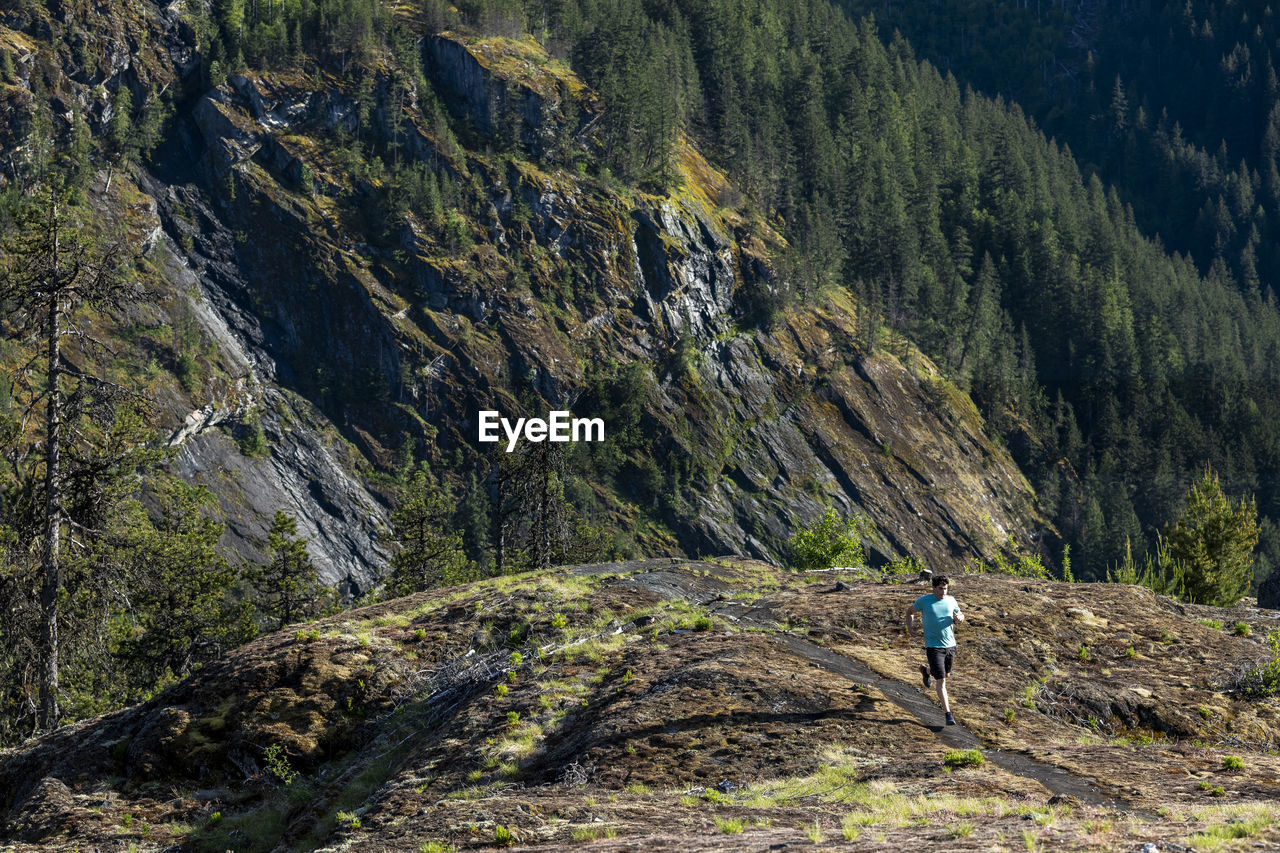 Man trail runs on a scenic alpine mountain trail in british columbia.