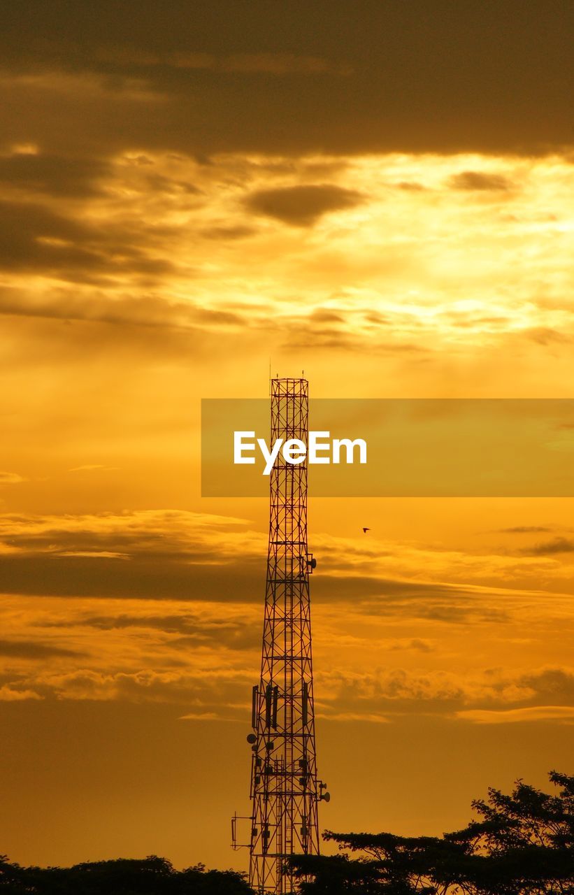 Silhouette crane against dramatic sky during sunset