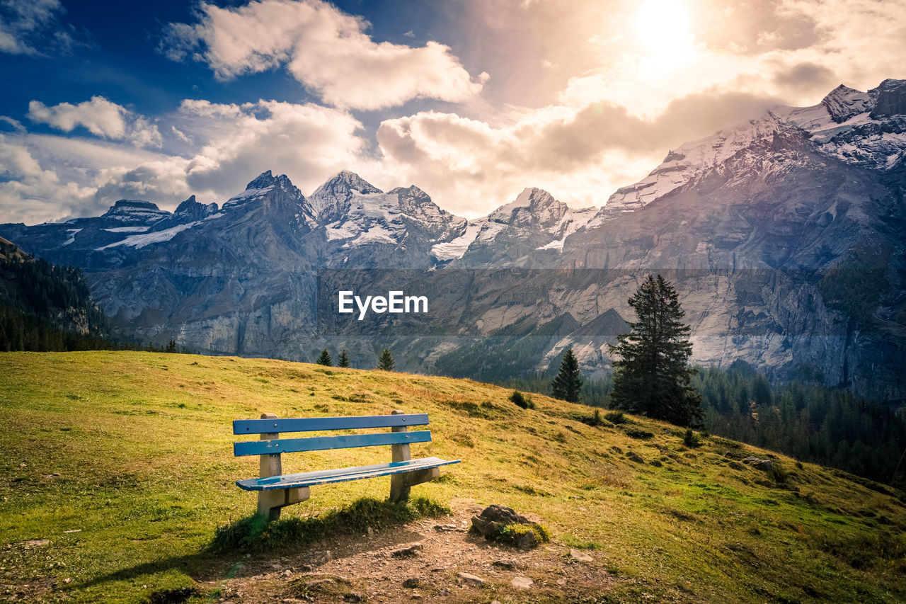 Empty bench on snowcapped mountains against sky