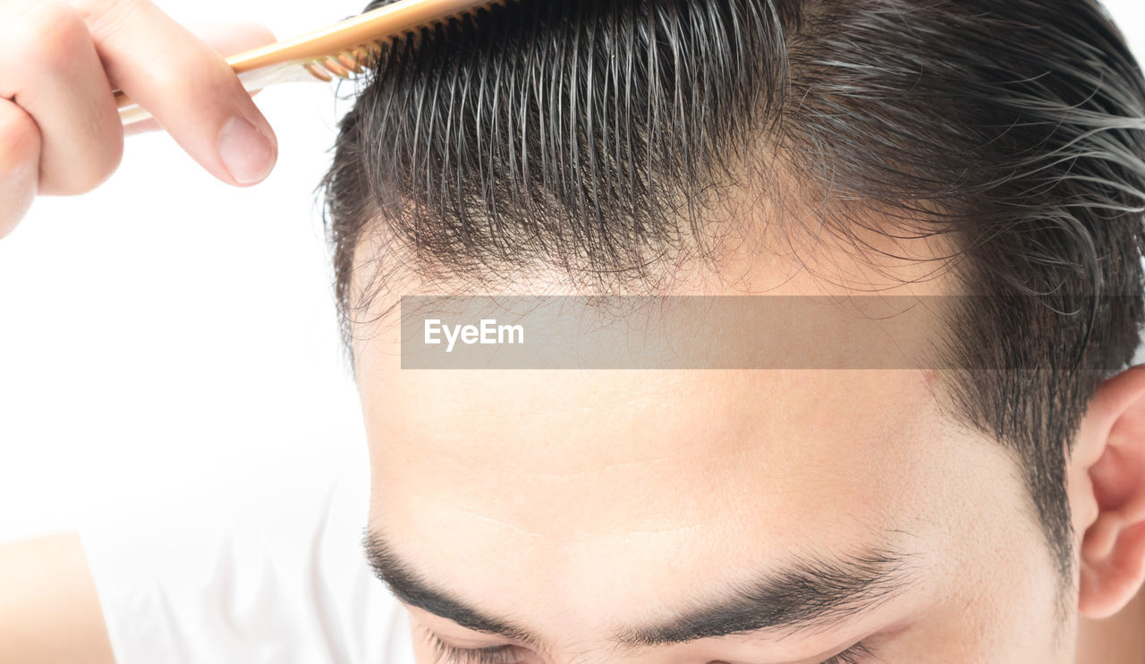 High section of man combing hair against white background