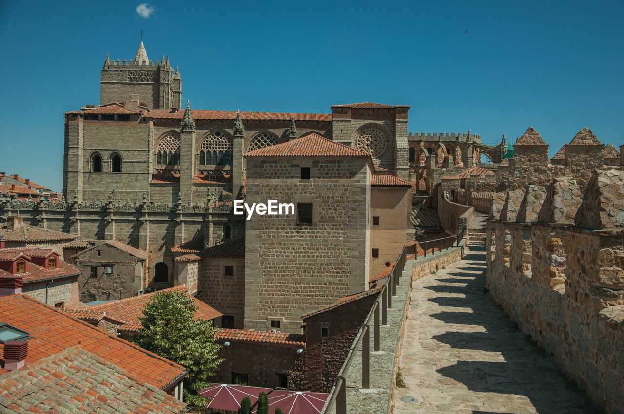 Pathway over stone wall with battlement around the town and side view of cathedral at avila, spain.