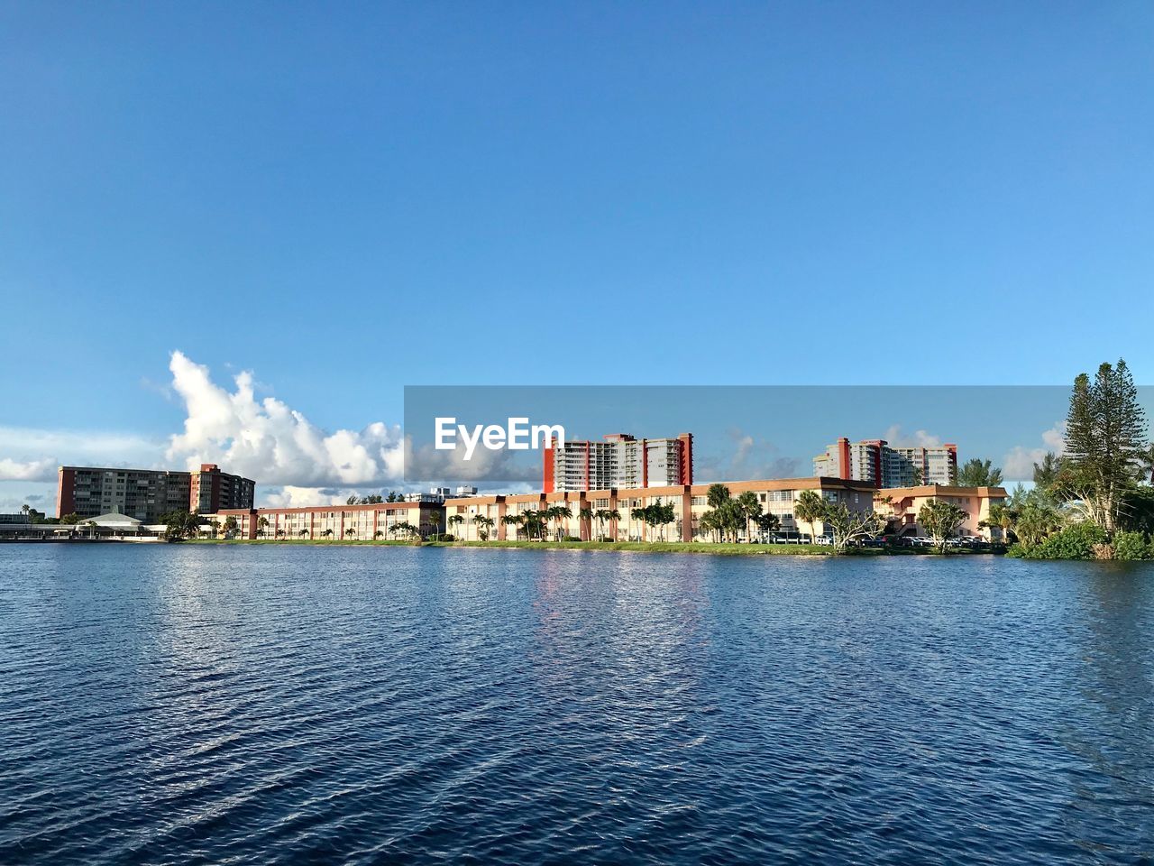 Scenic view of river by buildings against blue sky