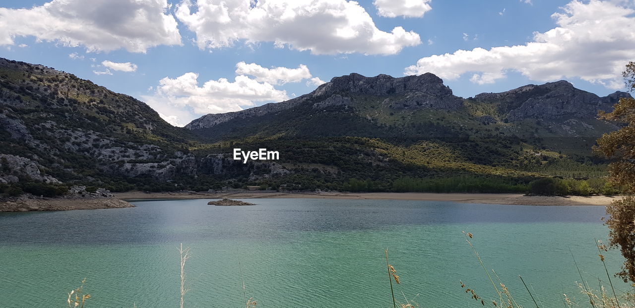 Scenic view of lake by mountains against sky