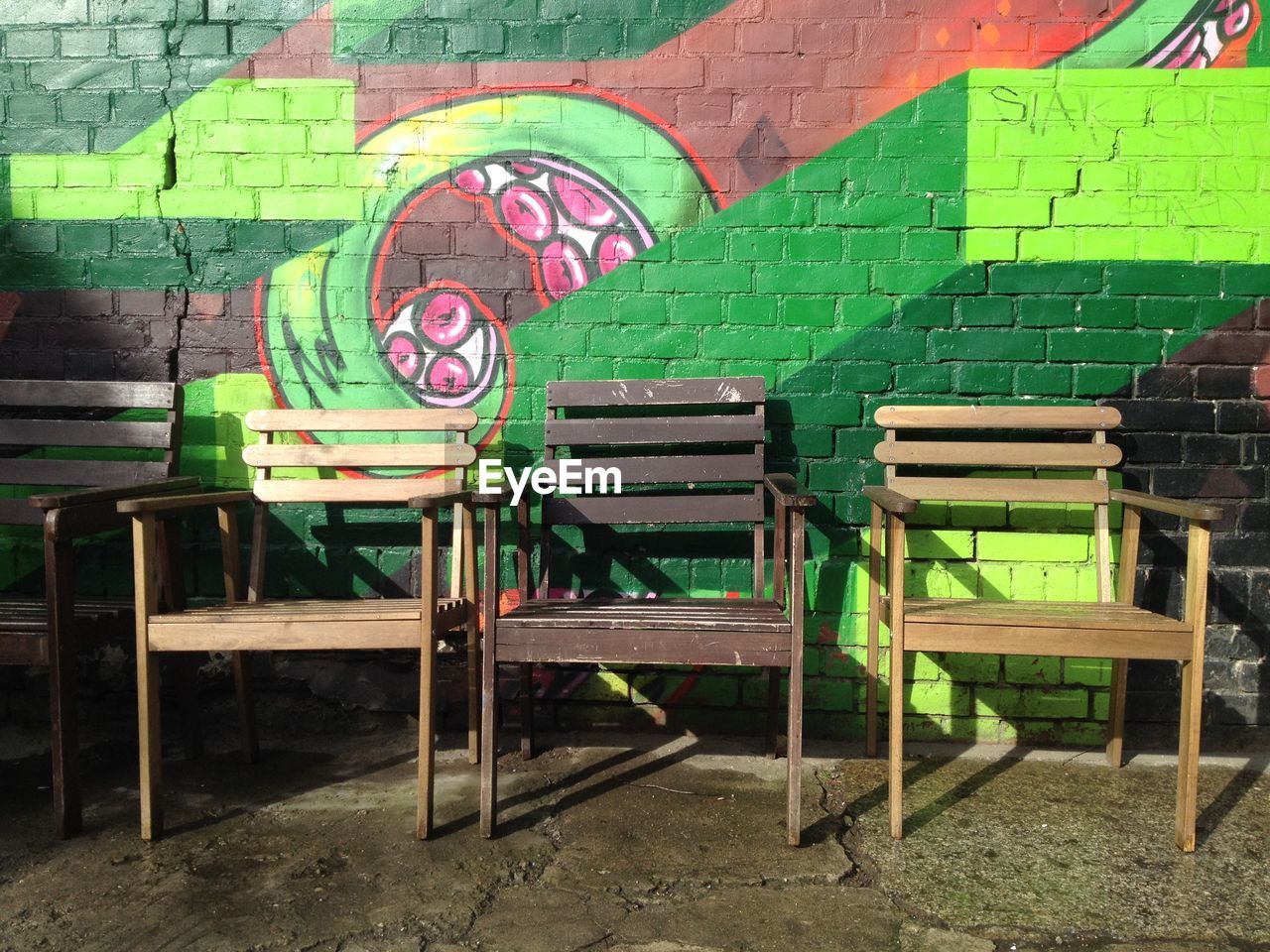 Wooden chairs against graffiti wall