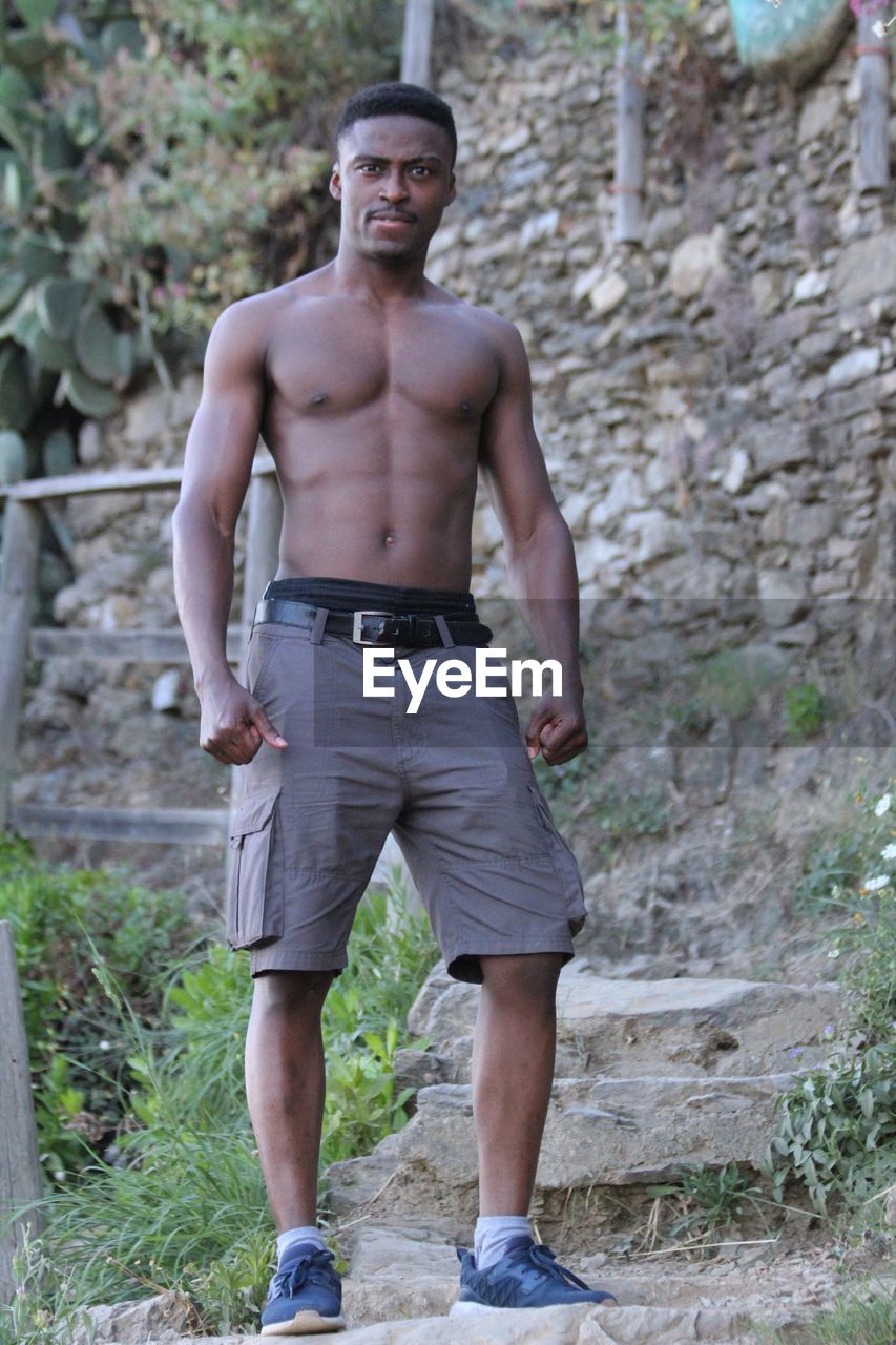 Portrait of young man standing against stone wall