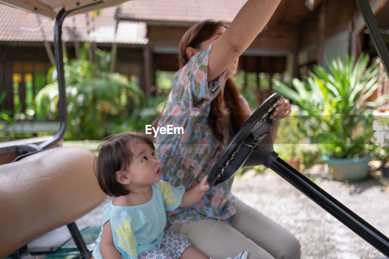 Woman sitting with girl on golf cart