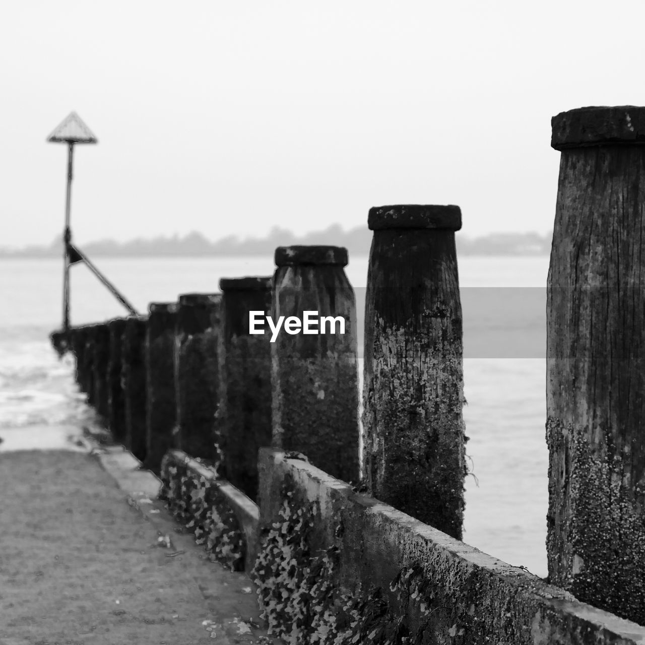 WOODEN POSTS ON BEACH AGAINST SKY