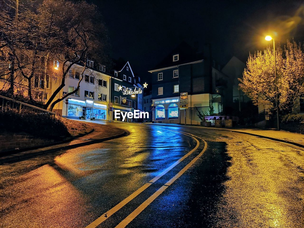 ILLUMINATED STREET BY BUILDINGS AT NIGHT