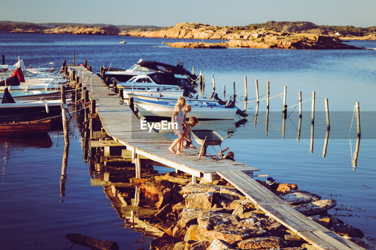 Boats moored on pier by sea against sky