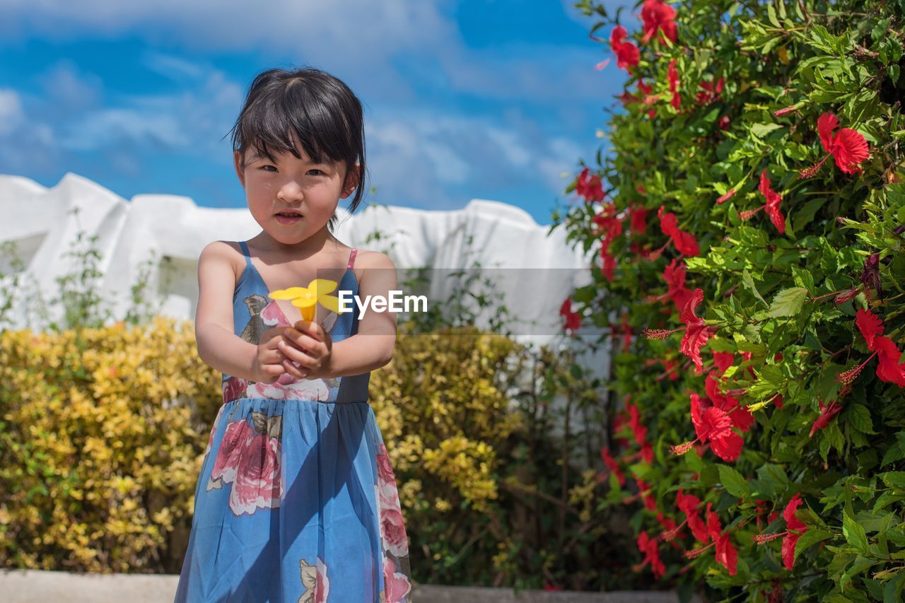 Portrait of cute girl holding yellow flower at park