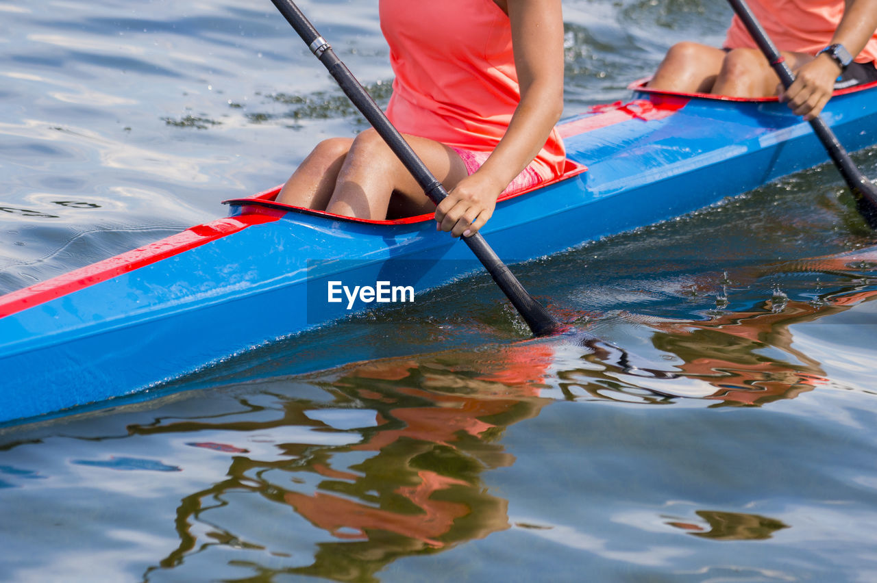 REAR VIEW OF WOMAN SITTING ON BOAT IN WATER