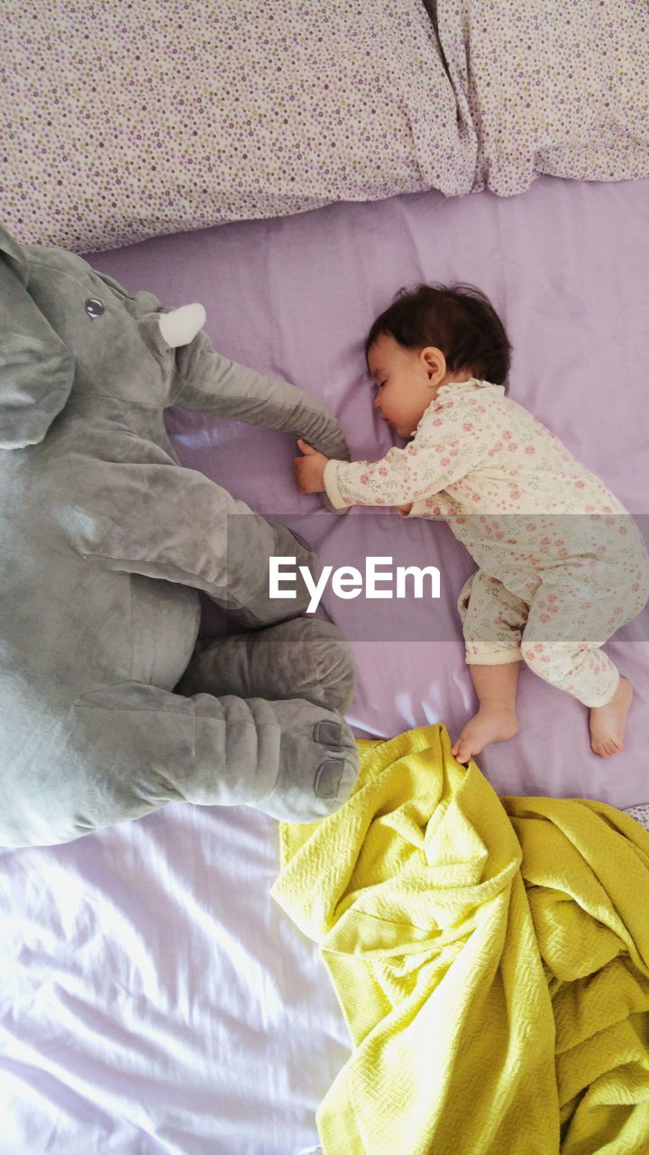 High angle view of baby girl sleeping with toy on bed at home