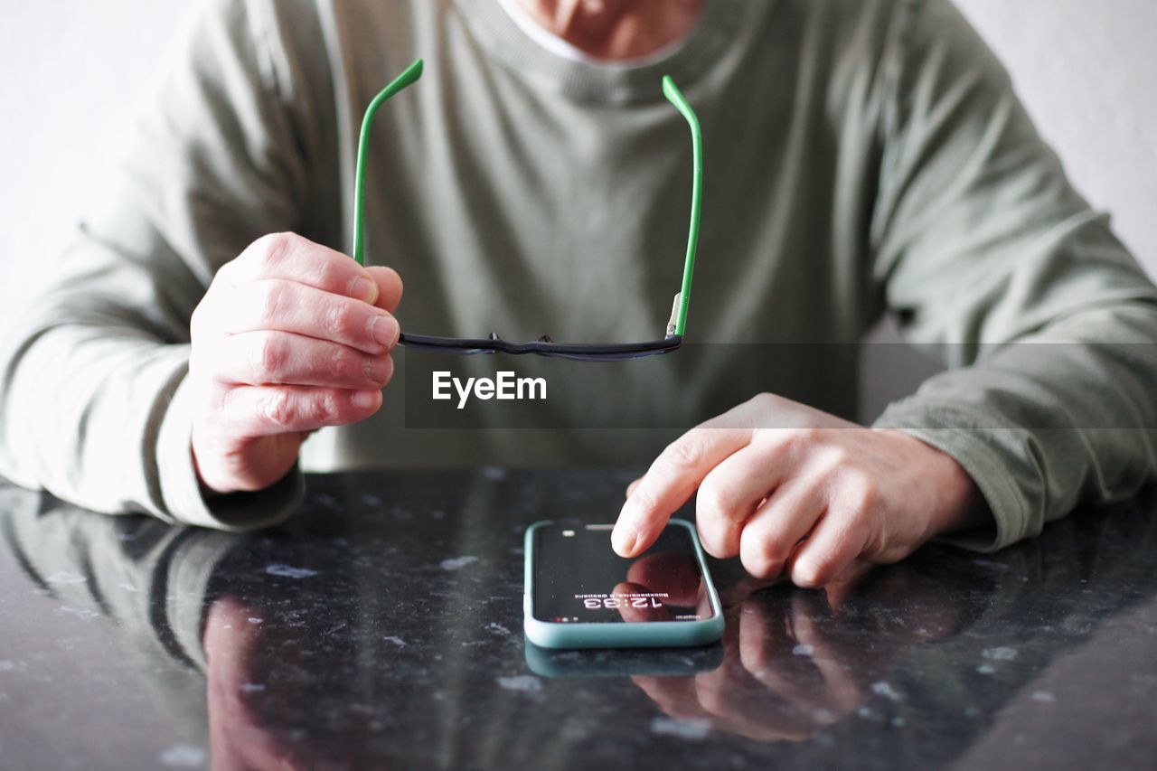 person, indoors, one person, adult, table, hand, technology, men, holding, business, writing, finger, clothing, close-up, occupation, wireless technology, front view, finance, selective focus