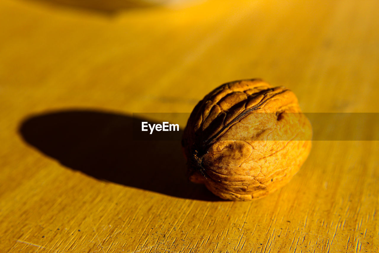 yellow, macro photography, close-up, leaf, food and drink, produce, food, wood, no people, healthy eating, plant, wellbeing, table, shadow, still life, fruit, freshness, indoors, flower, single object, nature, focus on foreground, nut, nut - food, selective focus