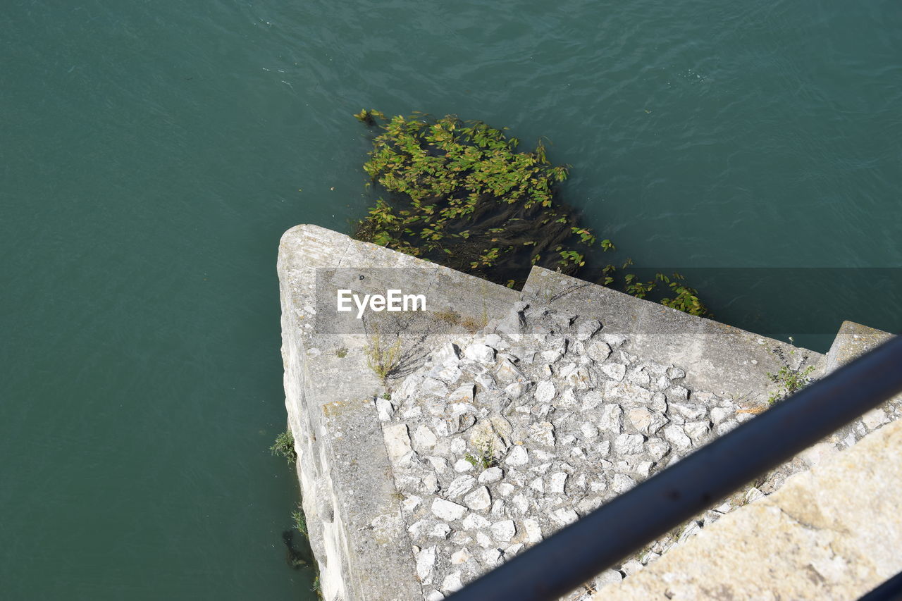 HIGH ANGLE VIEW OF ROCKS ON PIER AT LAKE