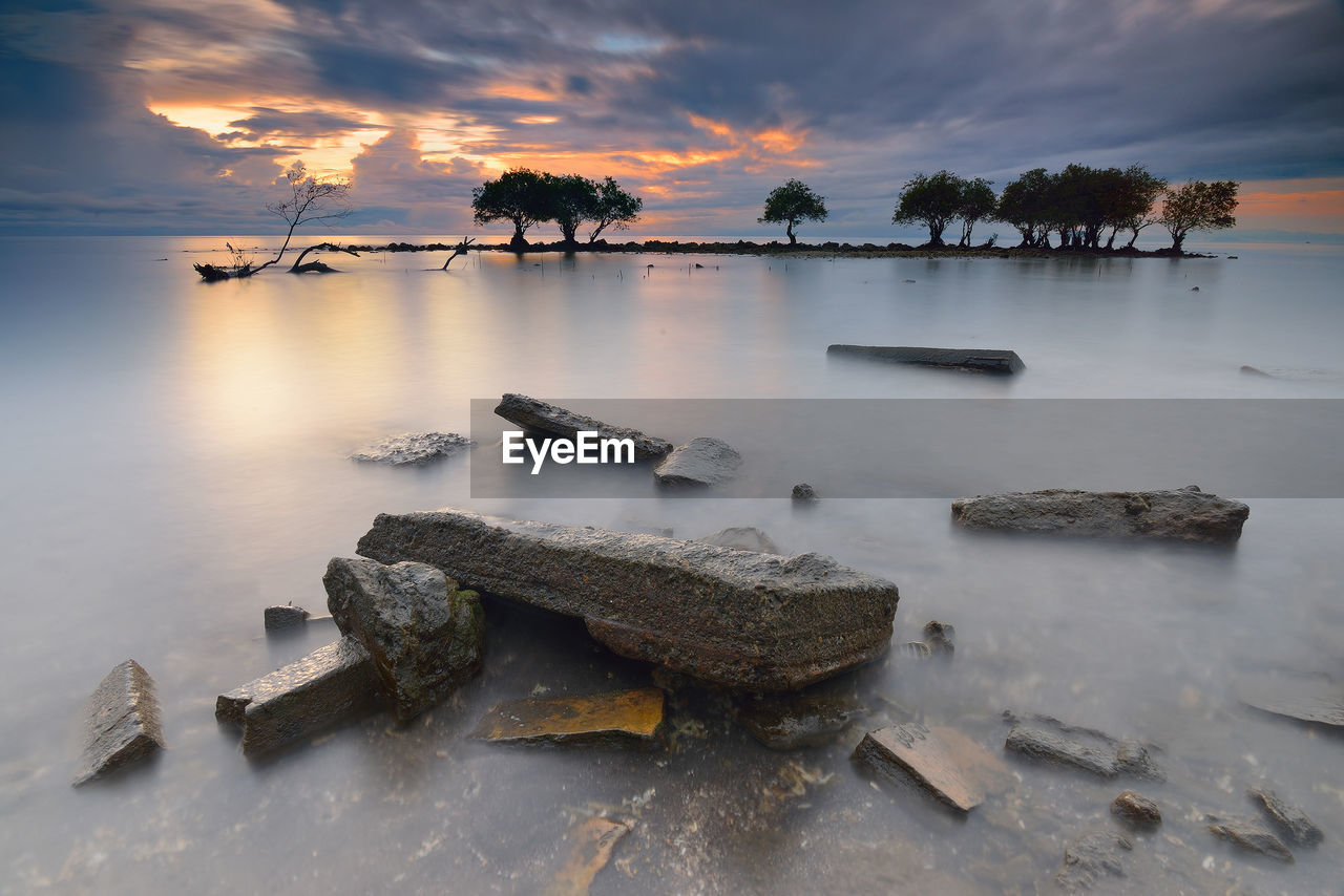 SCENIC VIEW OF SEA AGAINST CLOUDY SKY DURING SUNSET