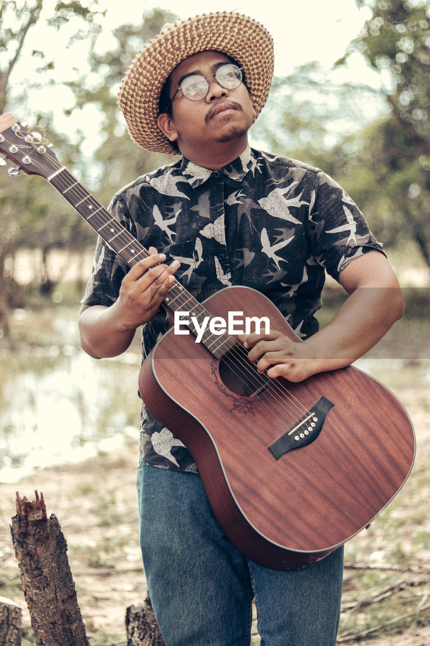 FULL LENGTH OF MAN PLAYING GUITAR ON ROCK