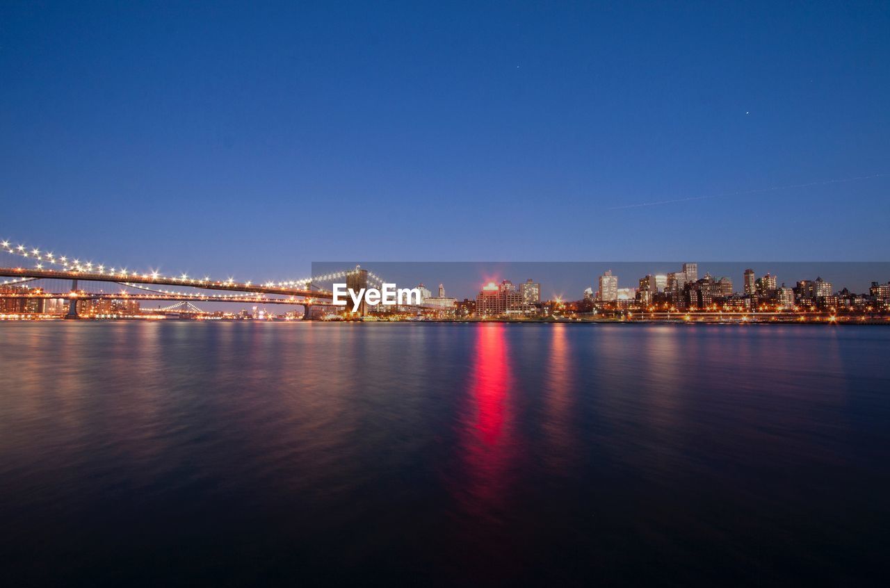 Illuminated brooklyn bridge with cityscape against sky at dusk