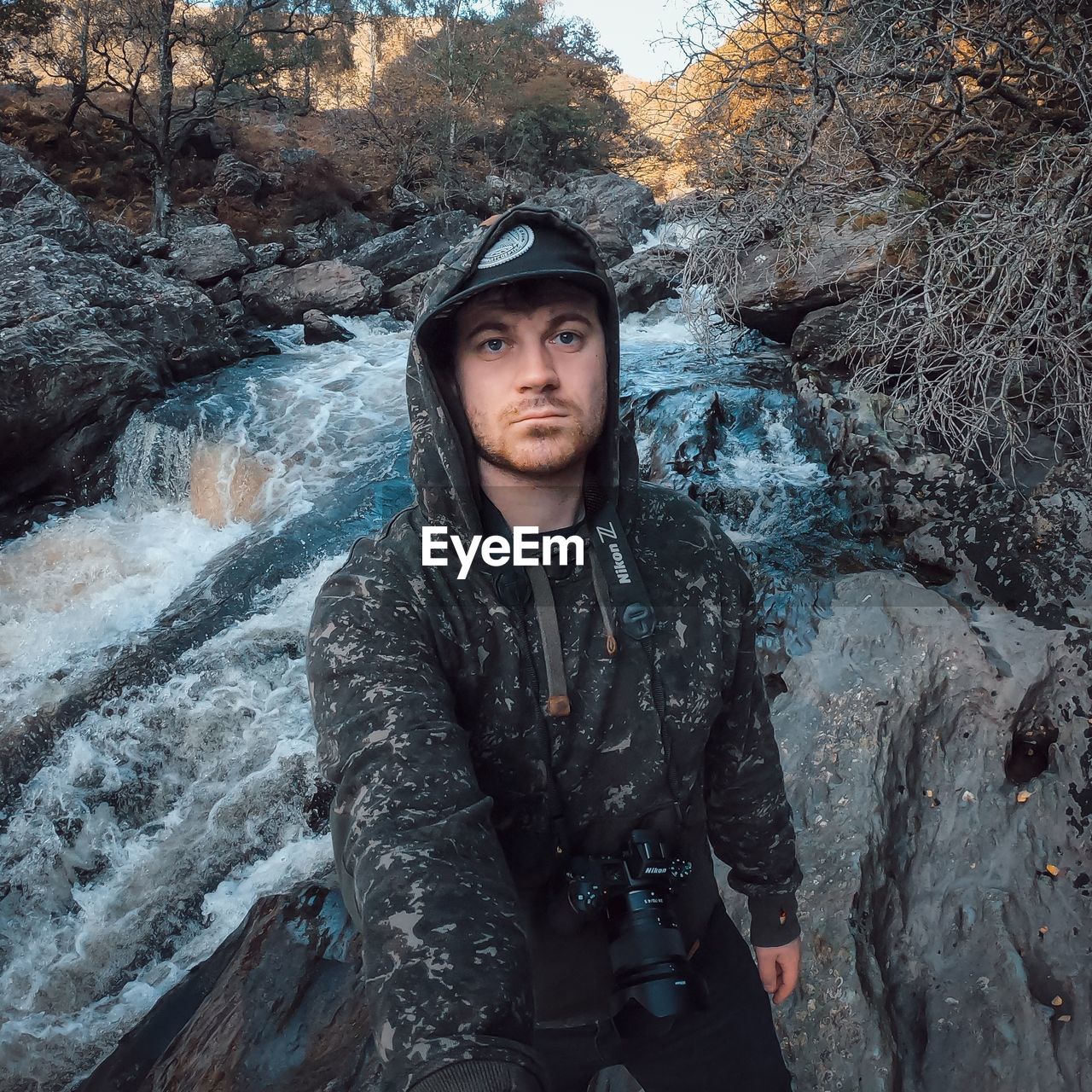 PORTRAIT OF YOUNG MAN STANDING ON ROCKS