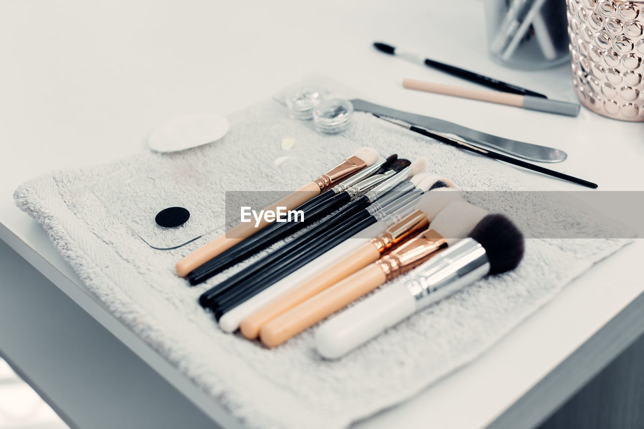 Collection of assorted brushes for makeup arranged on table in bright beauty salon