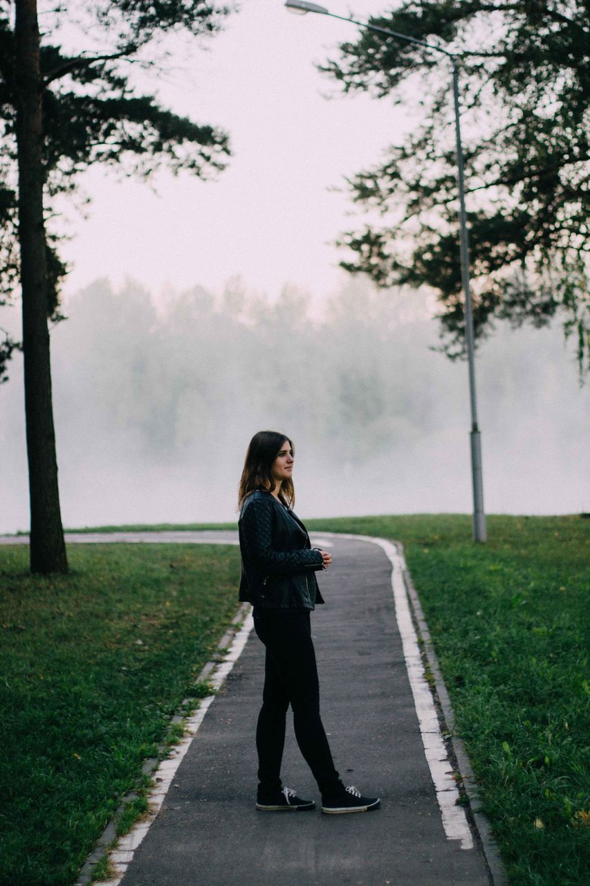 Full length side view of woman standing on road during foggy weather