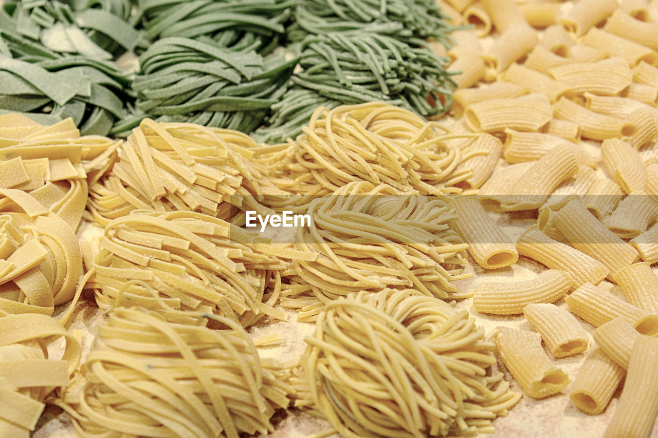 Fresh uncooked homemade pasta with spinach and wheat twisted on the table