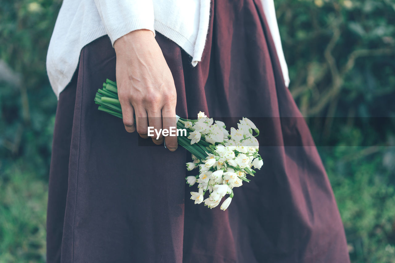 Closeup of female hand holding a bouquet of snowdrops in nature