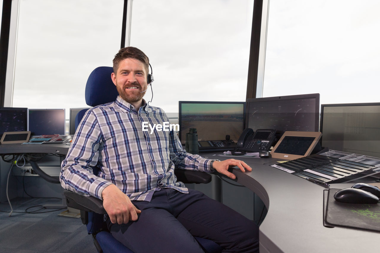 Bearded dispatcher sitting on chair in office