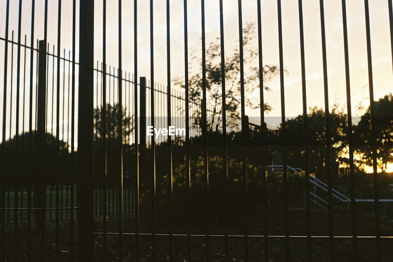 Silhouette fence against sky during sunset