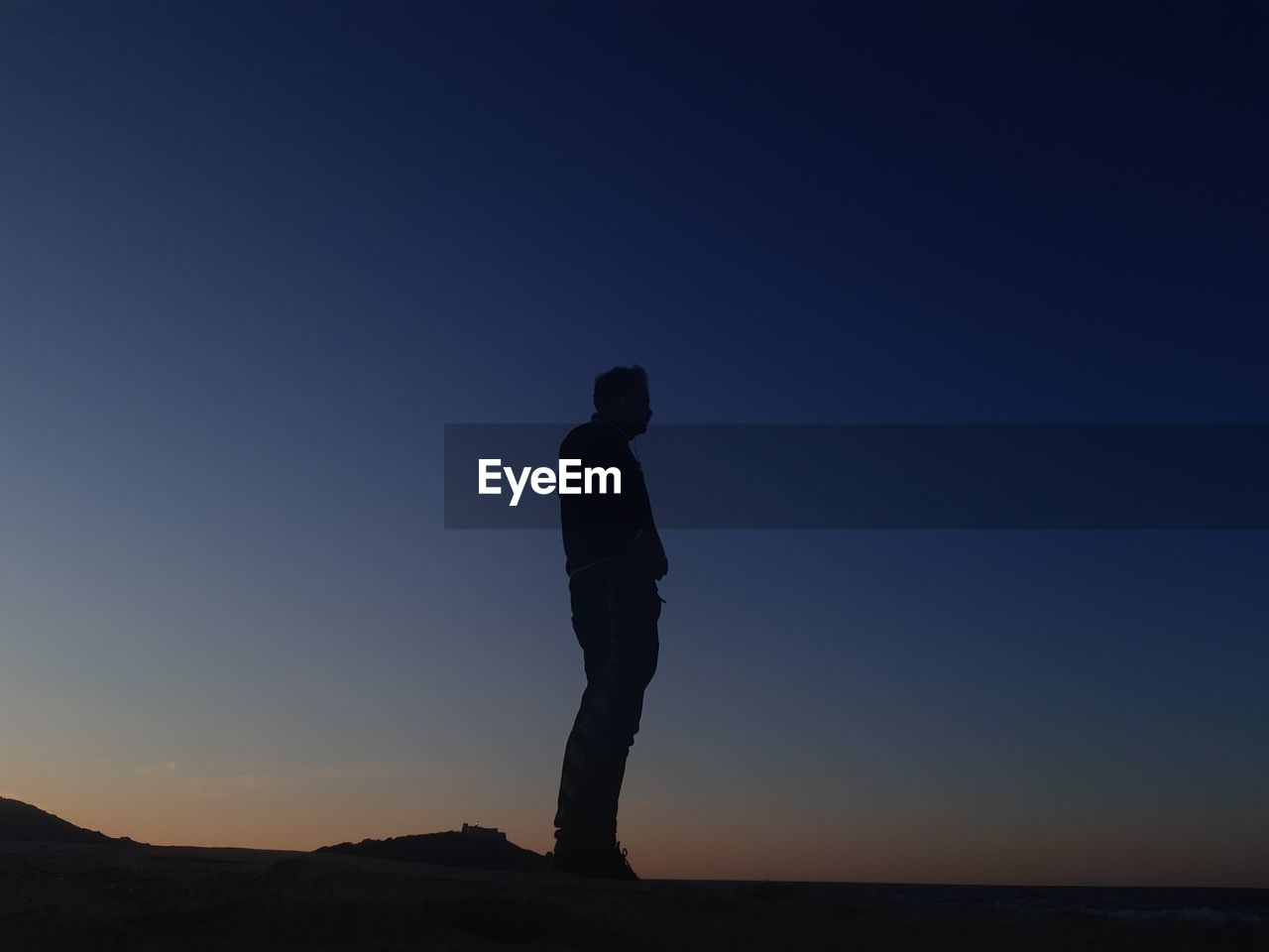 Silhouette man standing against clear sky during sunset