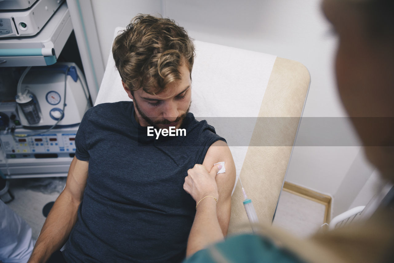 Cropped image of female nurse injecting male patient at hospital