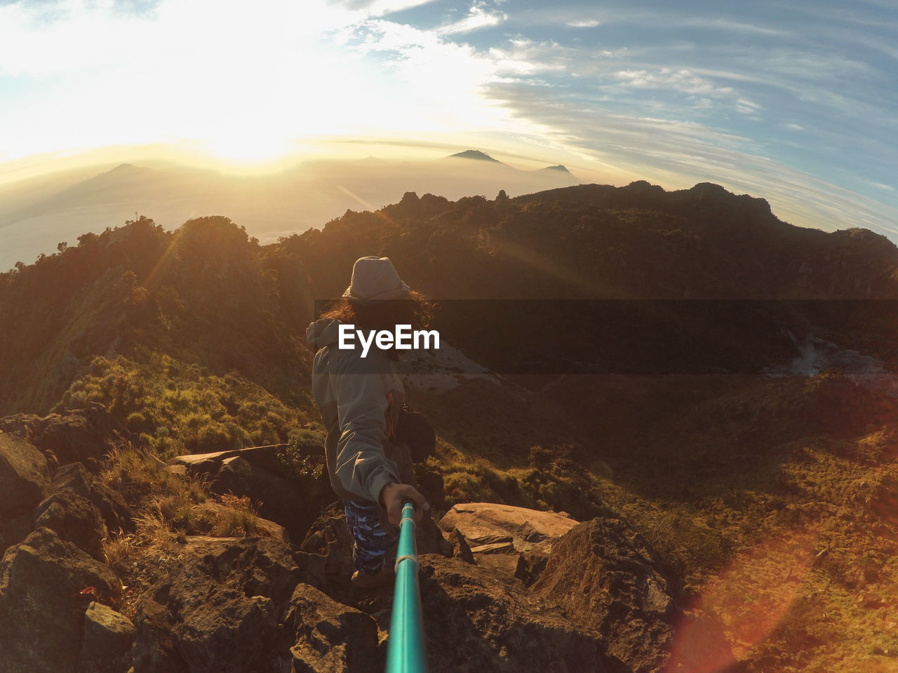 REAR VIEW OF MAN ON MOUNTAIN AGAINST SKY