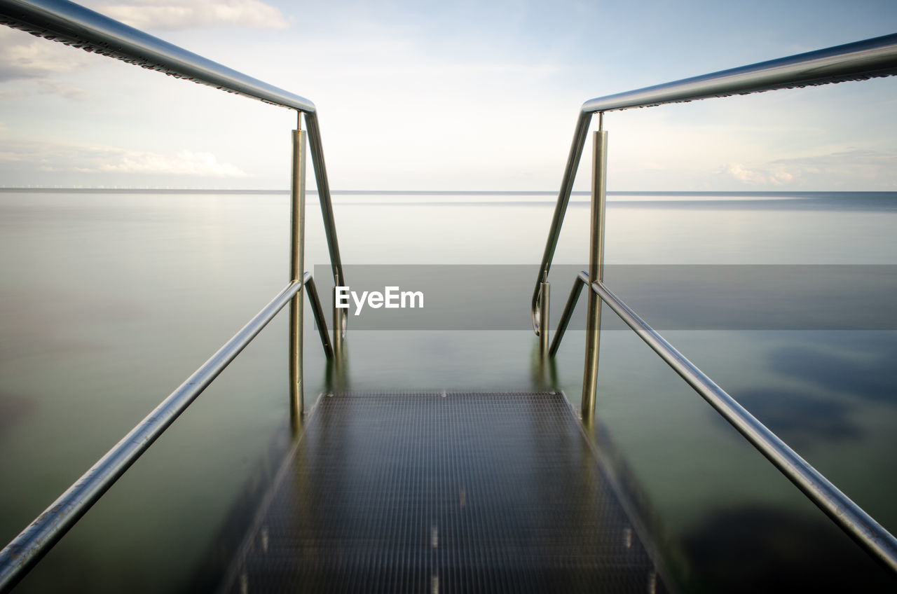 Close-up of steps by sea against sky