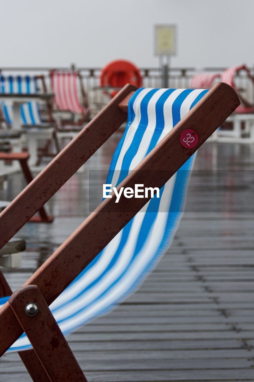 Close-up of deck chair on pier 