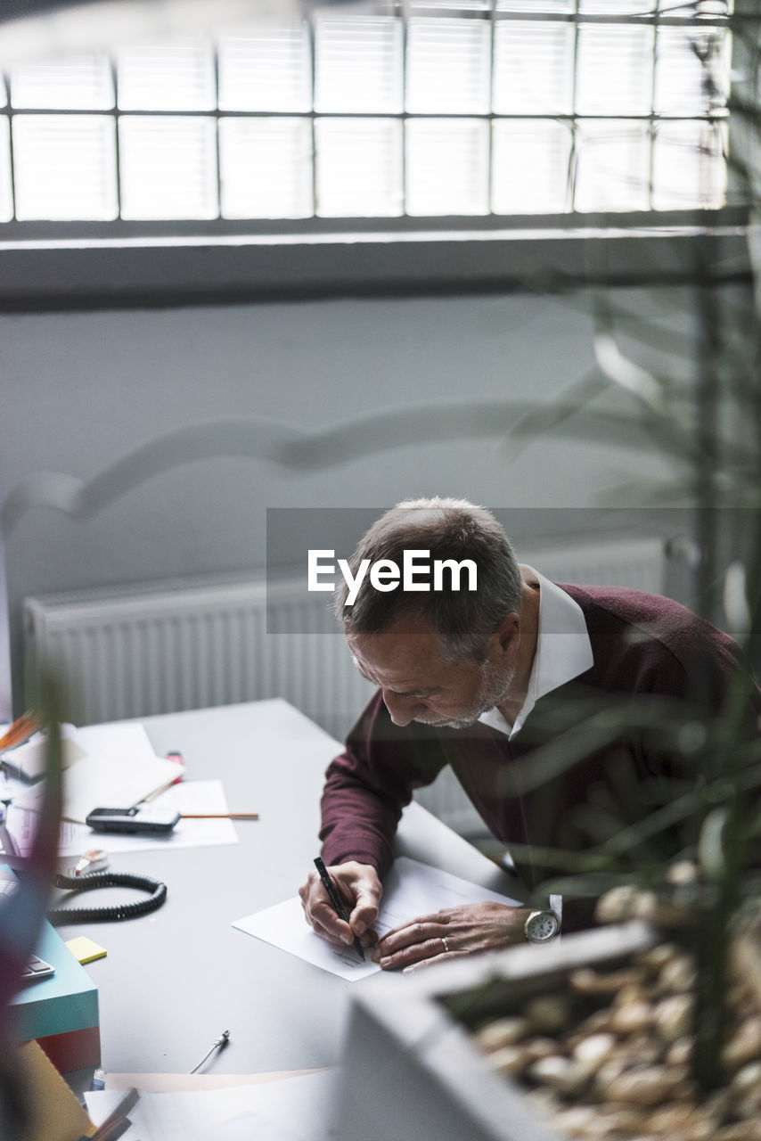 Mature man writing at desk