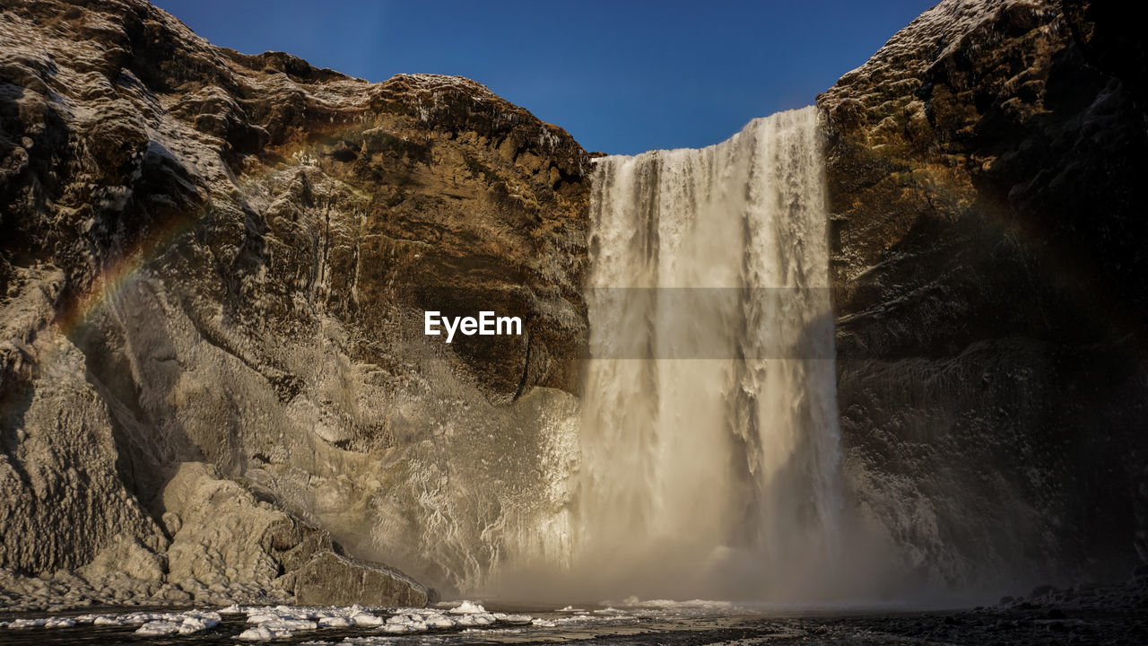 SCENIC VIEW OF WATERFALL AGAINST ROCK FORMATION