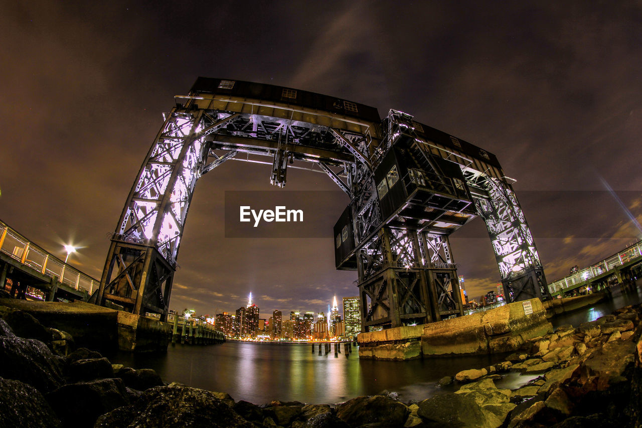 Low angle view of illuminated gantry over river at night