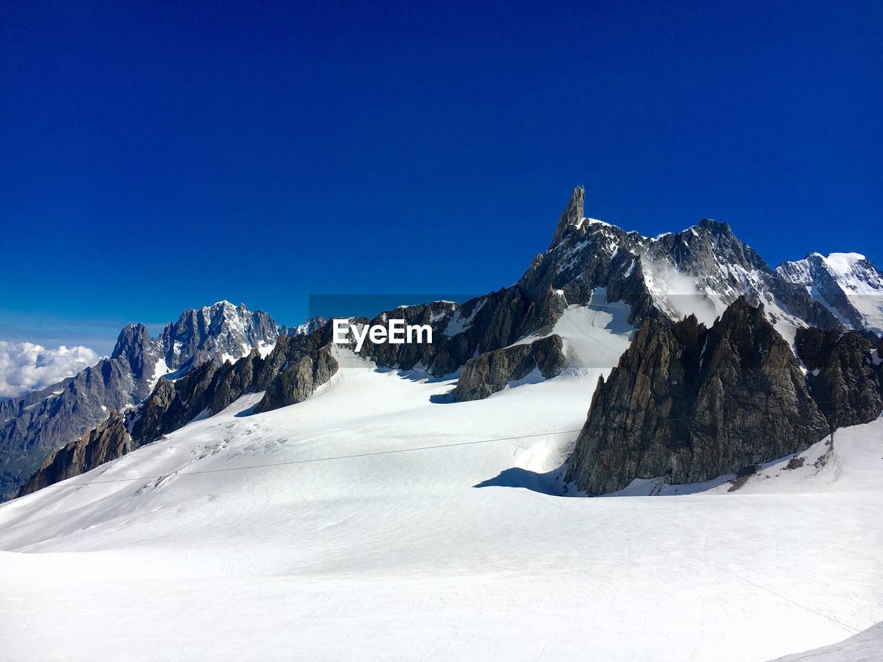 Scenic view of snow covered mountain against blue sky