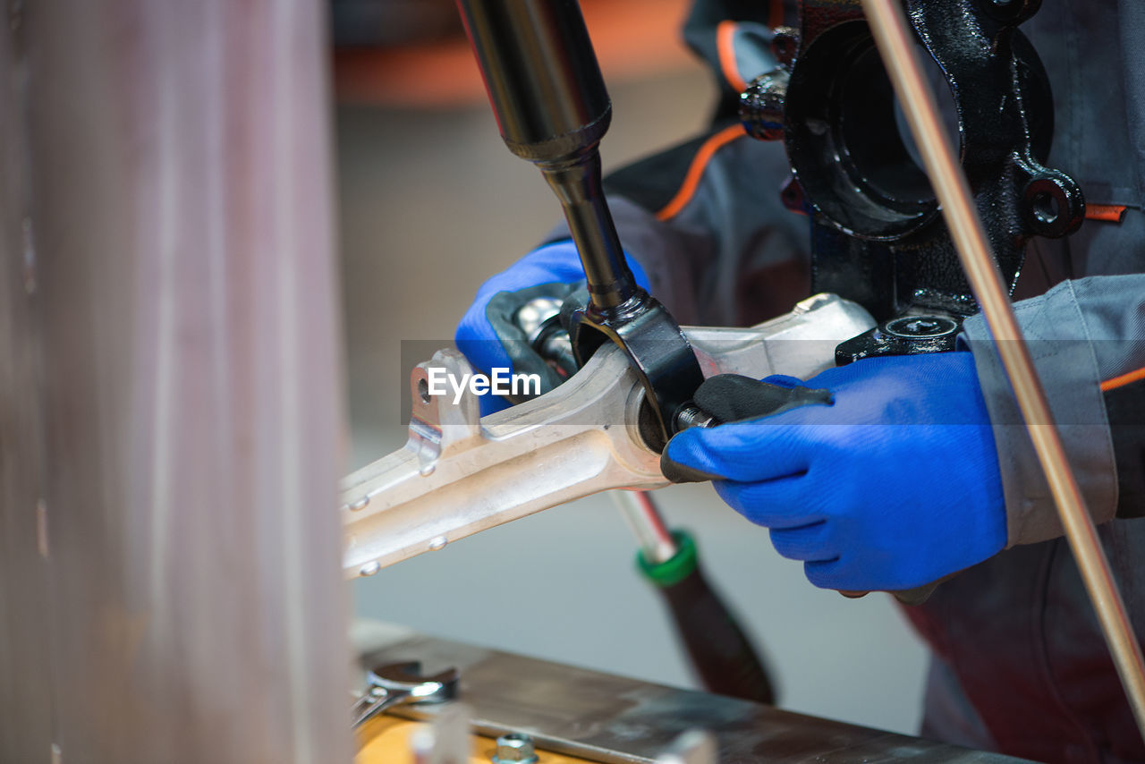 Close-up of manual worker repairing machinery while working in workshop