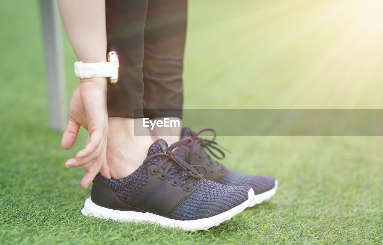 grass, footwear, shoe, human leg, adult, low section, one person, limb, lawn, human limb, green, plant, women, nature, sports, human foot, sneakers, leisure activity, day, outdoors, lifestyles, relaxation, sports shoe, activity, copy space, clothing, close-up, young adult, sunlight