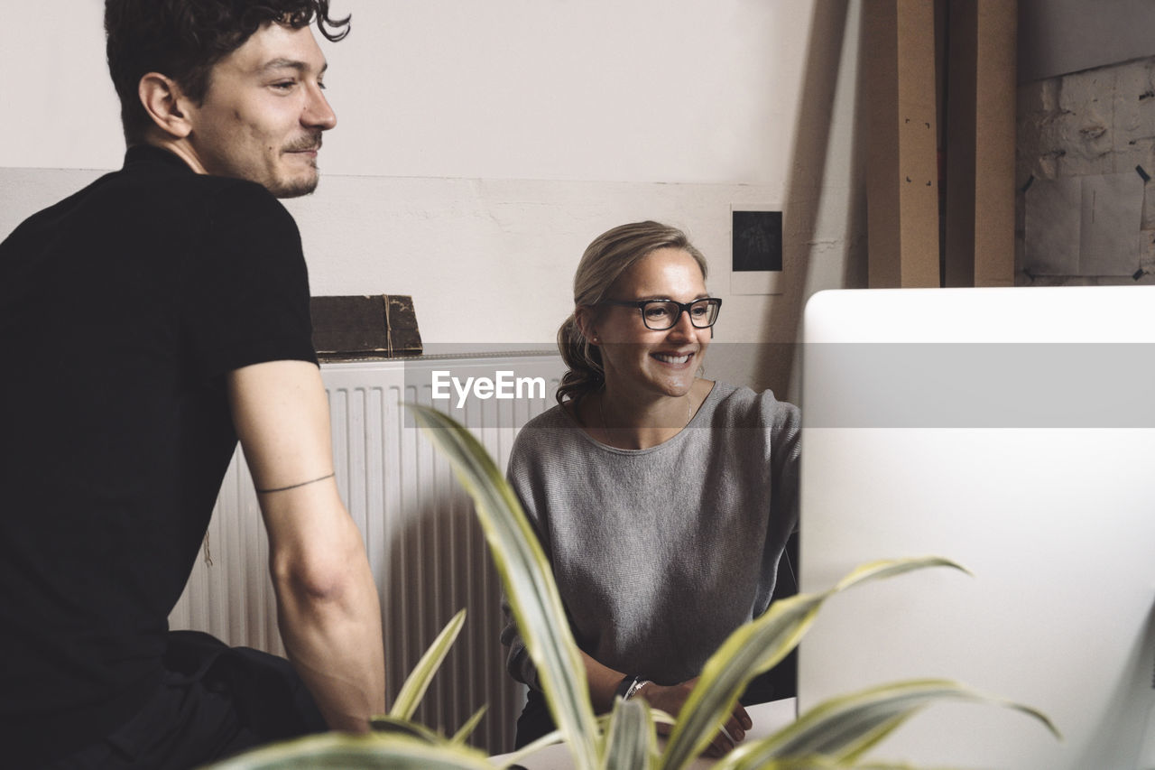 Smiling computer programmer with coworker at workplace