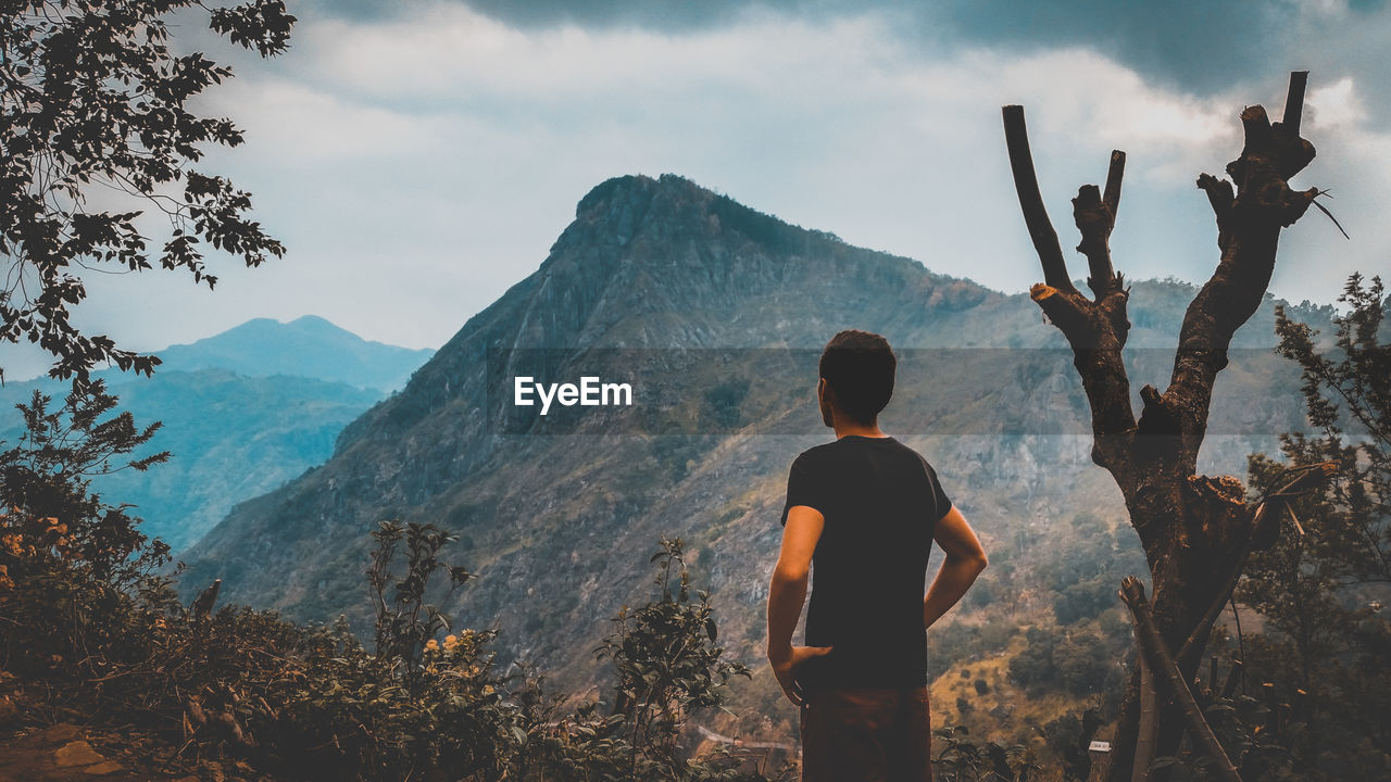 Rear view of man looking at mountains against sky