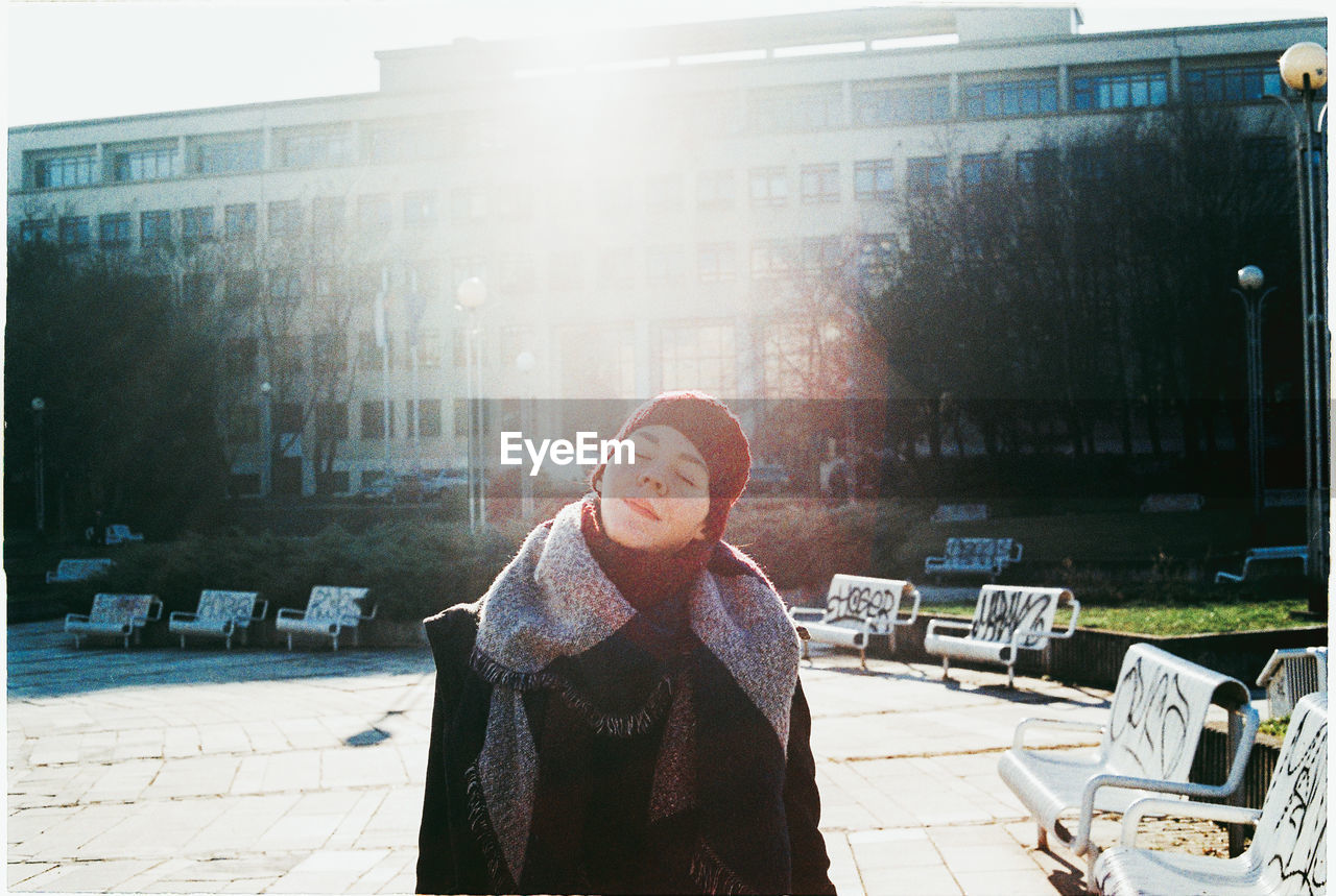 Woman with eyes closed against buildings