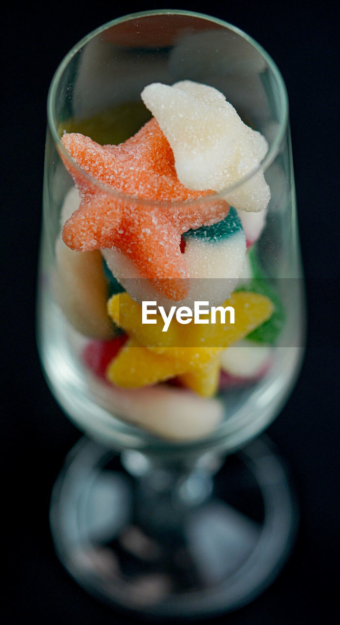 Close-up of sweet food in wineglass against black background