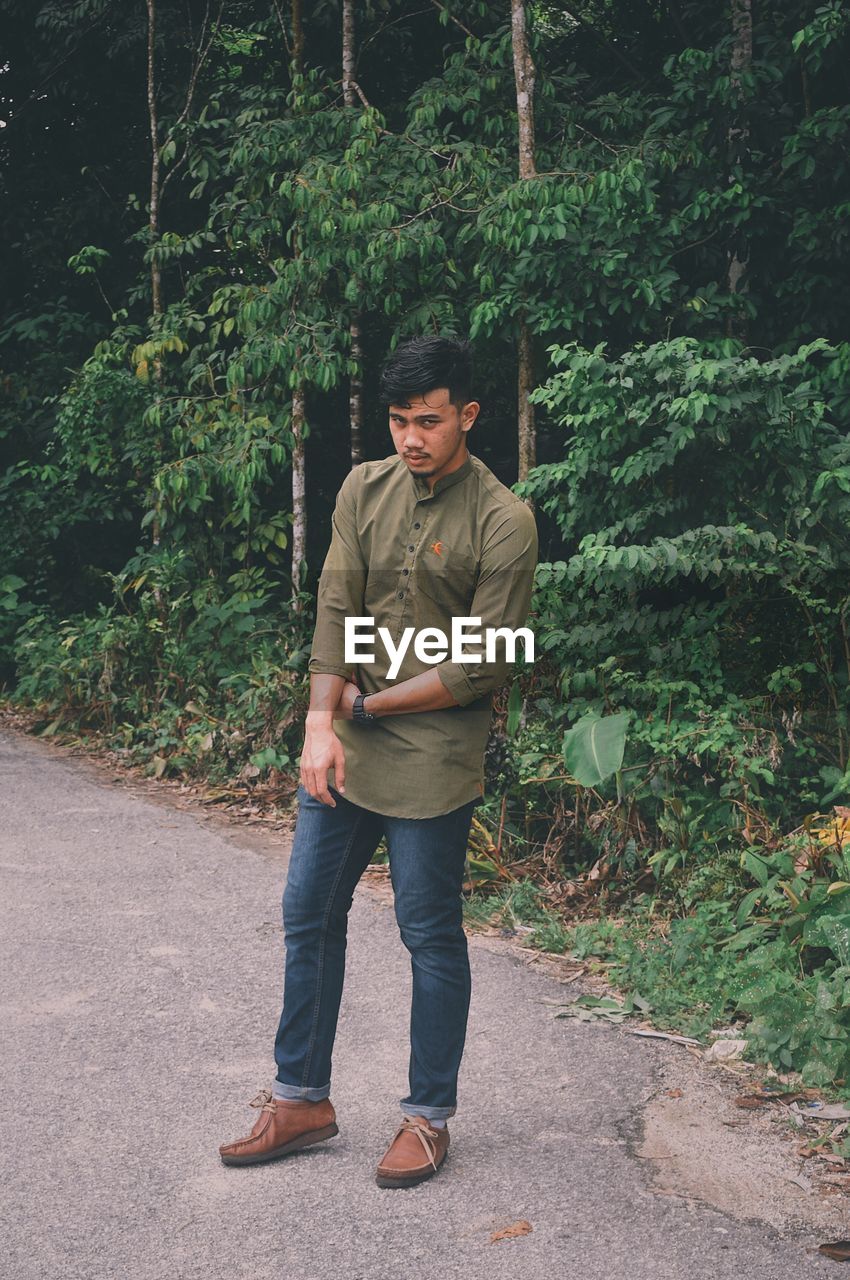 YOUNG MAN STANDING AGAINST TREES