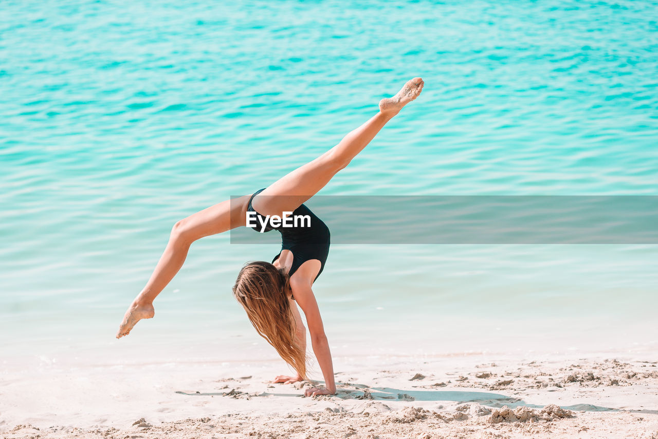 Full length of woman with arms raised on beach