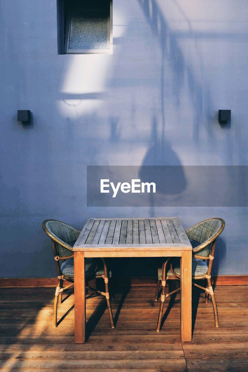 Empty chairs and table against wall