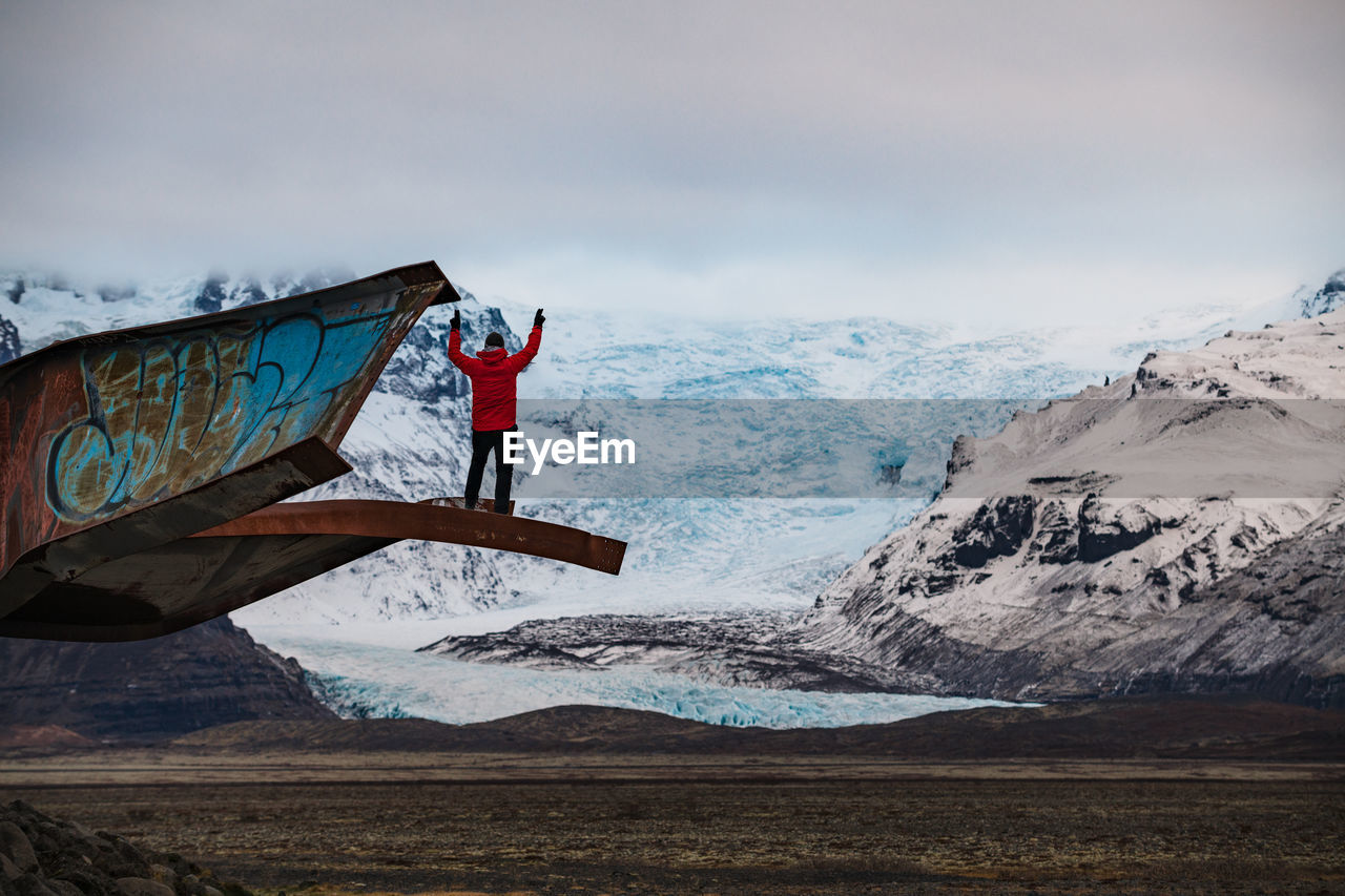 Person on steel construction near valley with iceberg between mountains in snow