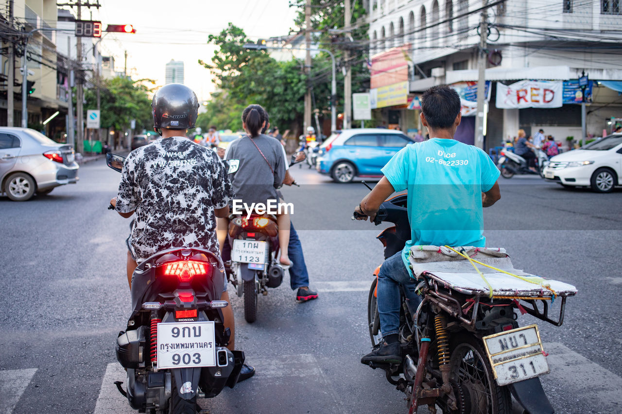REAR VIEW OF PEOPLE RIDING MOTORCYCLE ON ROAD